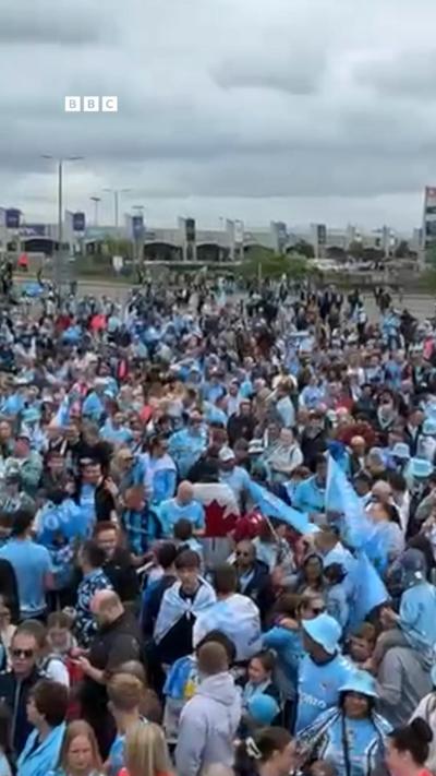 Crowds of people in sky blue shirts outside a football stadium