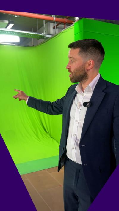 Man in suit points to green screen