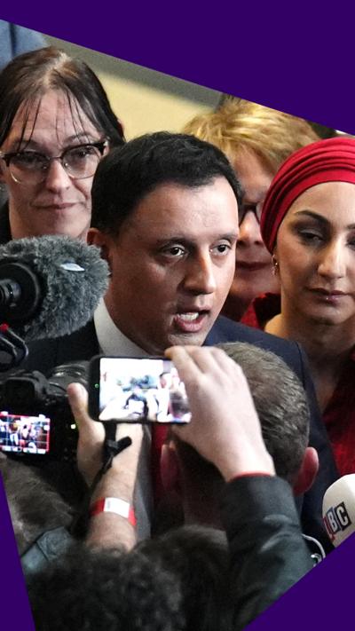 Anas Sarwar surrounded by journalists answering questions