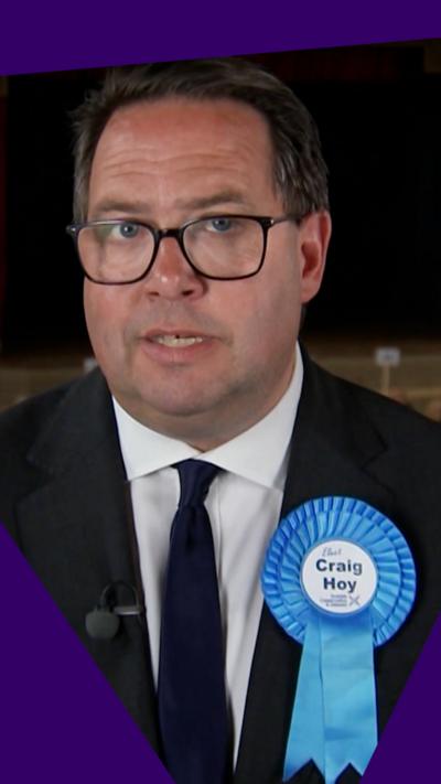 Craig Hoy looking at camera with blue badge on