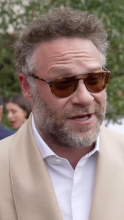 Close-up of Seth Rogen wearing beige suit and white shift on the red carpet
