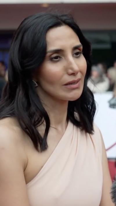 Close-up of Narges Rashidi wearing beige one-shoulder dress on the red carped