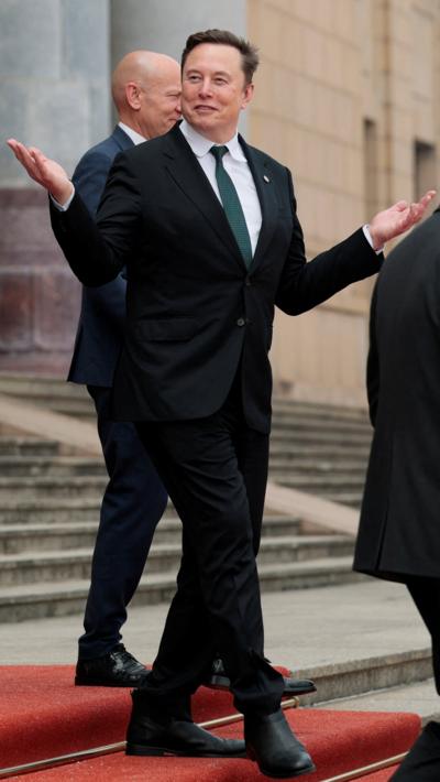 Elon Musk gestures wiht his hands as he walks down the steps of the Great Hall of the People in Beijing