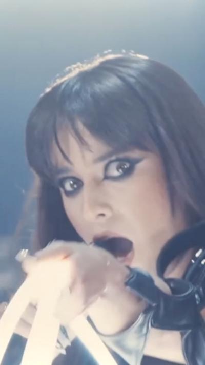 Romania female singer looking into the camera with her hand pointing forwards.