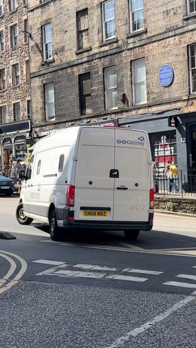 A white van is turning the corner on an Edinburgh street.