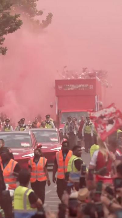 Sky turns red with Arsenal fan's flares as people and cars fill the street.