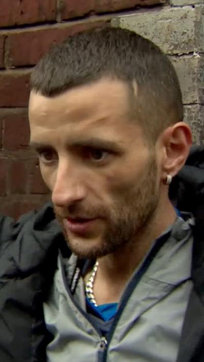 Close-up of resident being interviewed in front of his burnt house