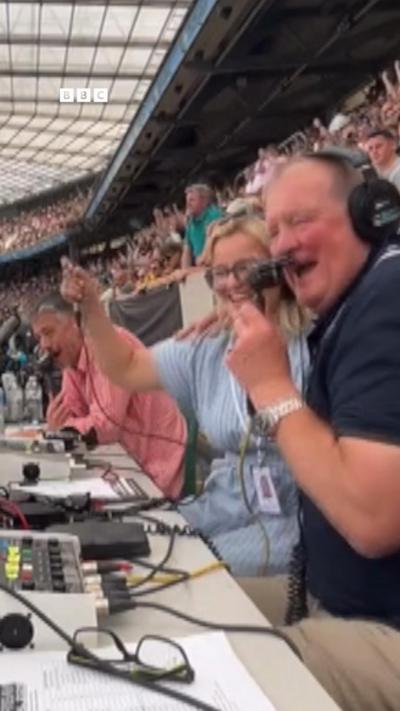 A joyous commentary team celebrates the end of a rugby match
