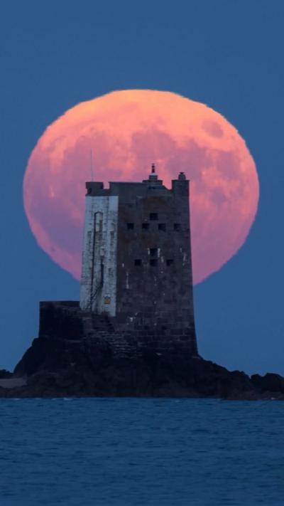 The moon glows orange behind Seymour Tower in Jersey