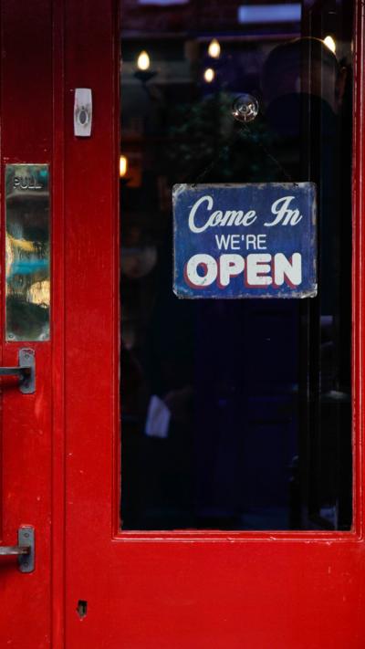 A pub door with a 'Come in we're open' sign