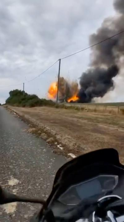 Explosion seen across a field with plume of smoke rising above it