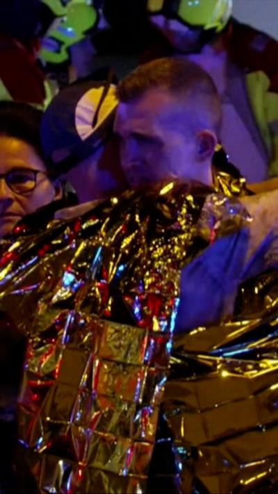 Two men hug in foil blankets.