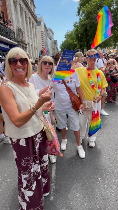 Ladies stand waving Pride flags in centre of Norwich