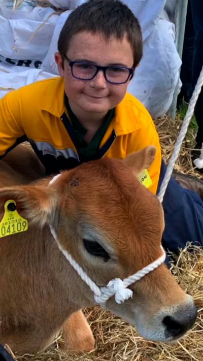 Smiling boy with glasses posing with a young calf
