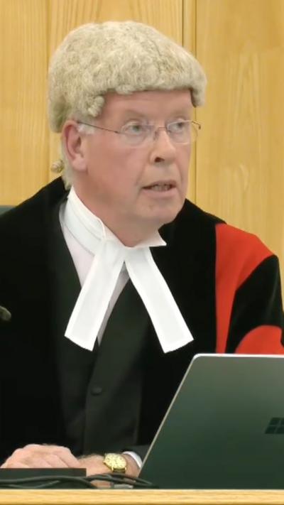 A judge sits in court behind a laptop