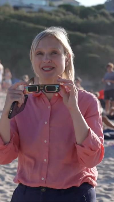 Rebecca Morrell holding up a pair of solar glasses
