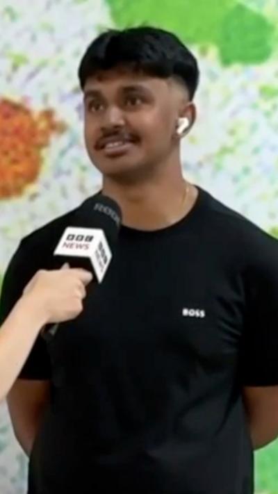 Man with brown hair and black t-shirt speaking with BBC microphone next to his face