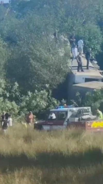 People stand on an overturned train