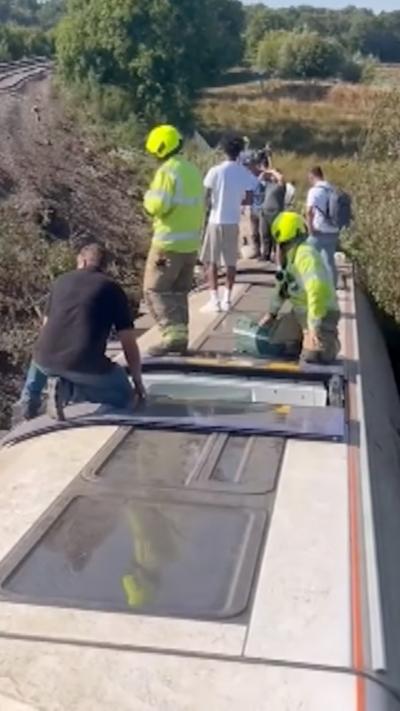 Passengers standing on top of a derailed train carriage