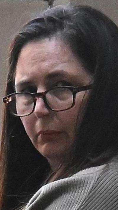 Erin Patterson wearing glasses looking over her shoulder