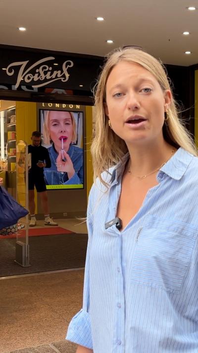 londe woman in a blue shirt stands outside a department store