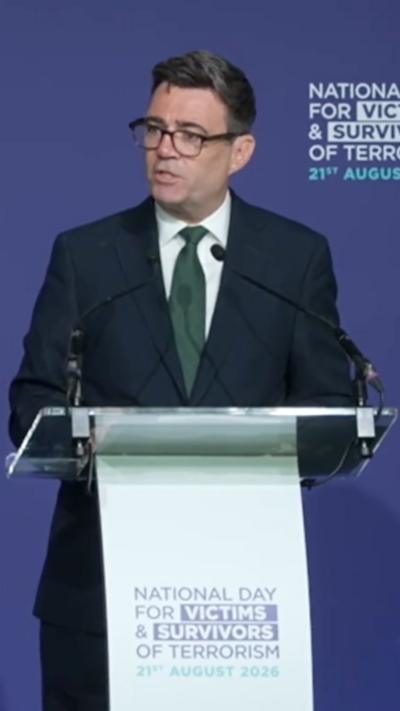 Andy Burnham stands behind a podium