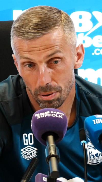 Gary O'Neil wears a blue top and sits behind a microphone