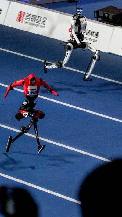 Two humanoid robots run on a racing track.