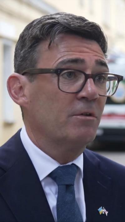 UK Prime Minister Andy Burnham wearing glasses, navy suit and tie and white shirt