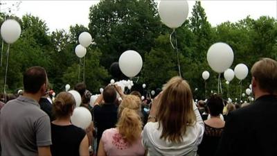 People wait to release balloons in honour of the dead and injured of Love Parade
