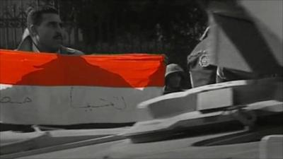 Protester with flag and passing tank