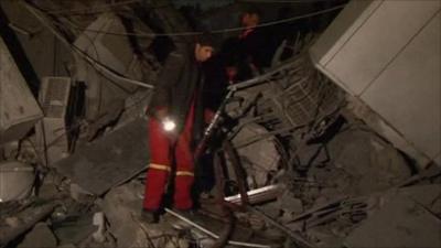 Man walks on rumble of bombed compound