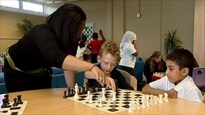 Teacher and pupils playing chess in school