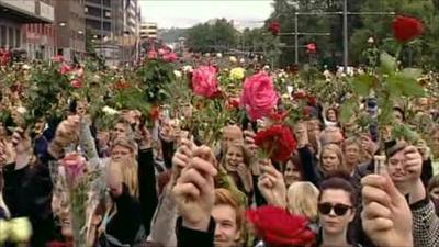 People in Oslo hold up roses