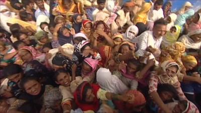 An aerial view of a crowd awaiting food delivered being by helicopter