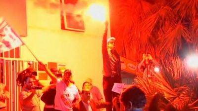 Tunisian's celebrate and one holds up a flare