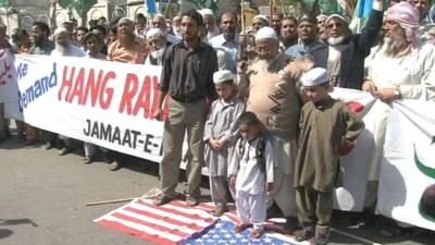 Pakistani protesters standing on US flag