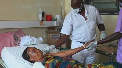 Woman lying in hospital bed treated by doctors