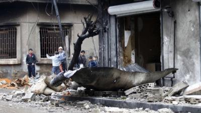 Children next to a damaged building in Homs