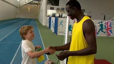 Athlete shakes hand with school boy