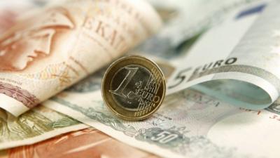 A one Euro coin is displayed on a Greek Drachma and Euro banknotes