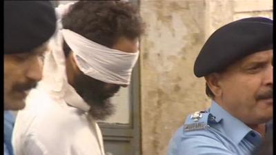 Imam in blindfold and handcuffs