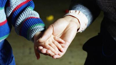 Adult and child holding hands