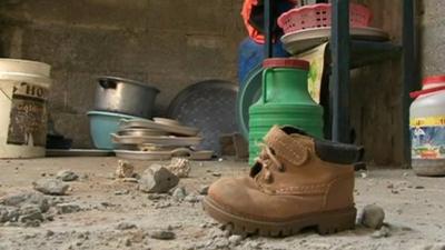 Child's boot and household items in rubble