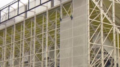 Workers at the Olympic Stadium dismantling wrapping