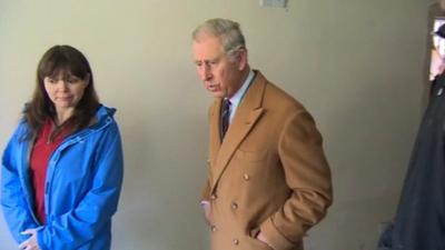 Prince Charles in a flooded house standing beside the owner