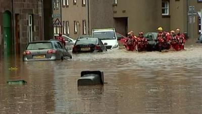 Rescue teams dragging inflatable down flooded street