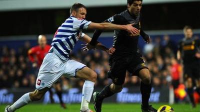 Liverpool's Luis Suarez (r) glides past QPR's Clint Hill