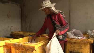 A man rummages through a bin in Bangkok