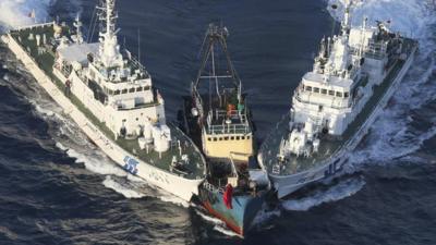 A fishing boat is surrounded by two Japanese Coast Guard patrol boats